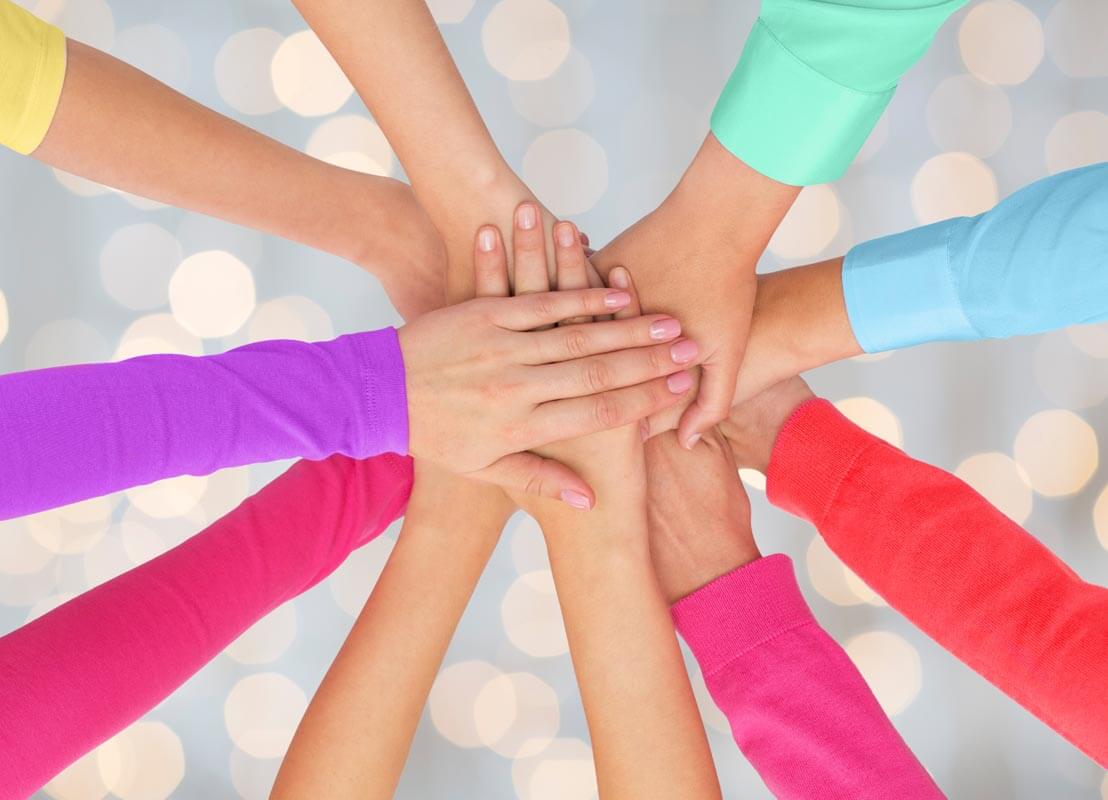 people, gesture, gay pride and homosexual concept - close up of women hands in rainbow clothes on top of each other over holidays lights background